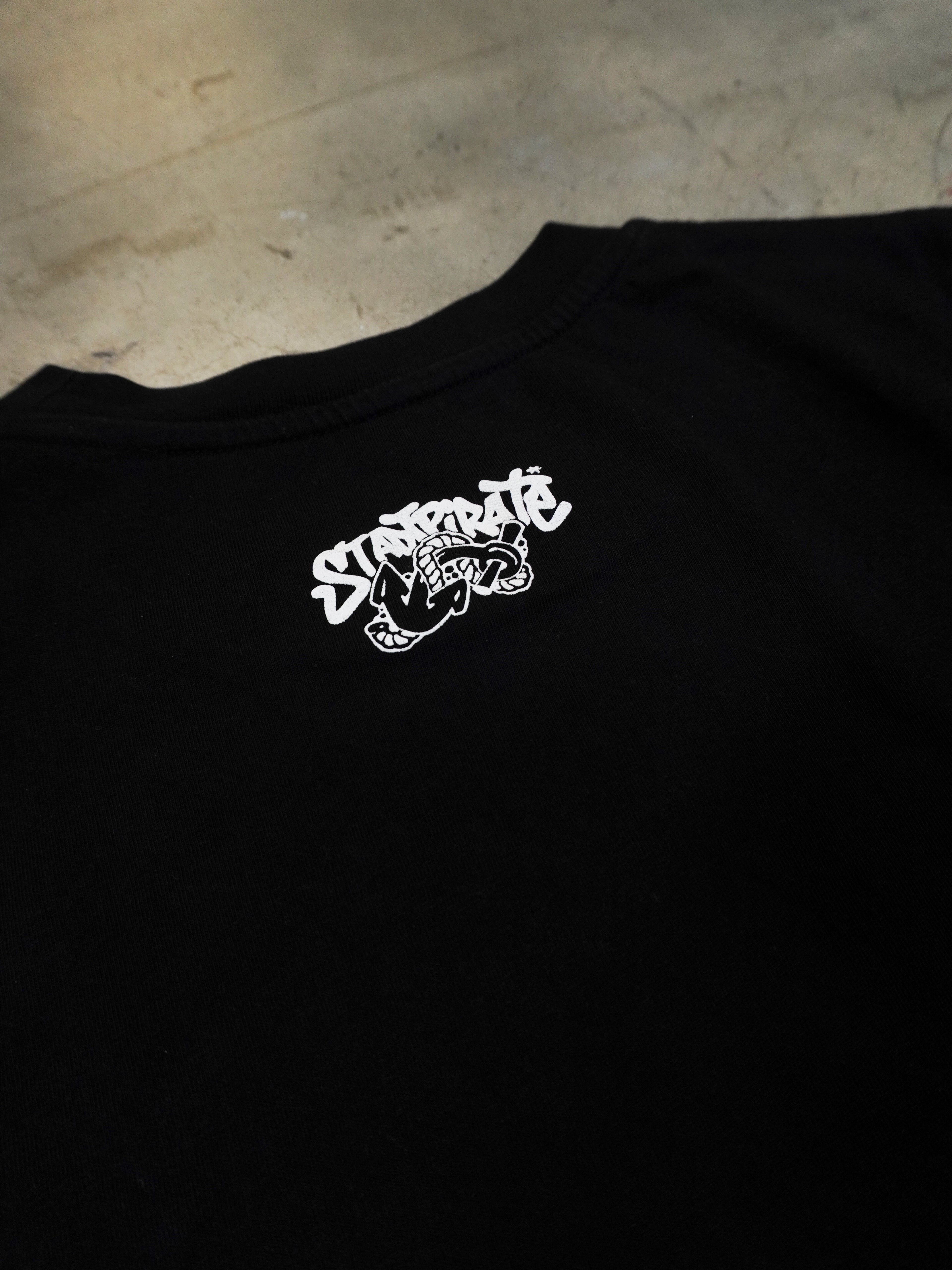 Detailaufnahme des kleinen Prints im Nackenbereich des schwarzen T-Shirts