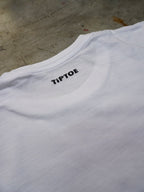 Detailaufnahme des kleinen Nackenlogos auf weissem T-Shirt