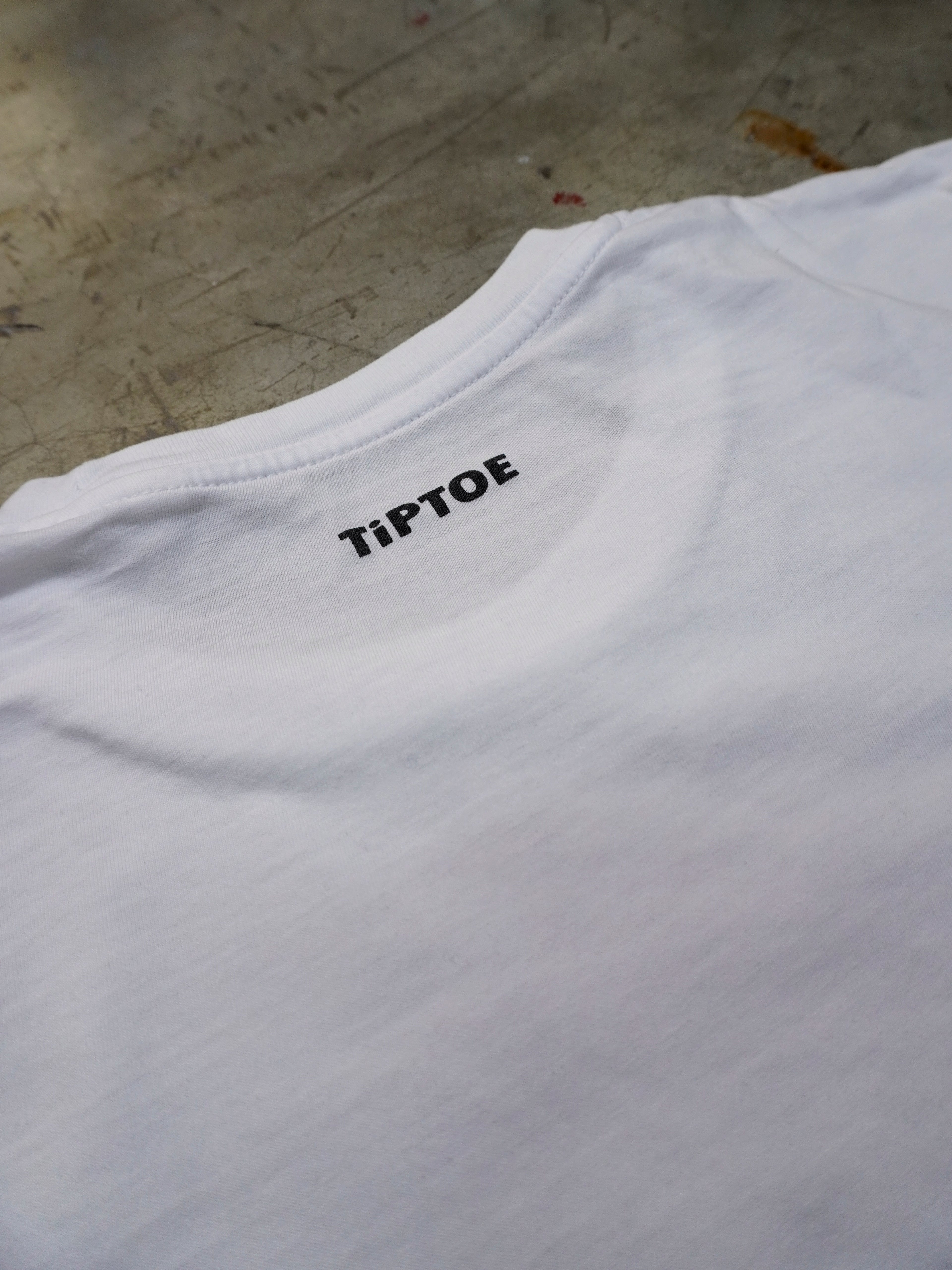 Detailaufnahme des kleinen Nackenlogos auf weissem T-Shirt