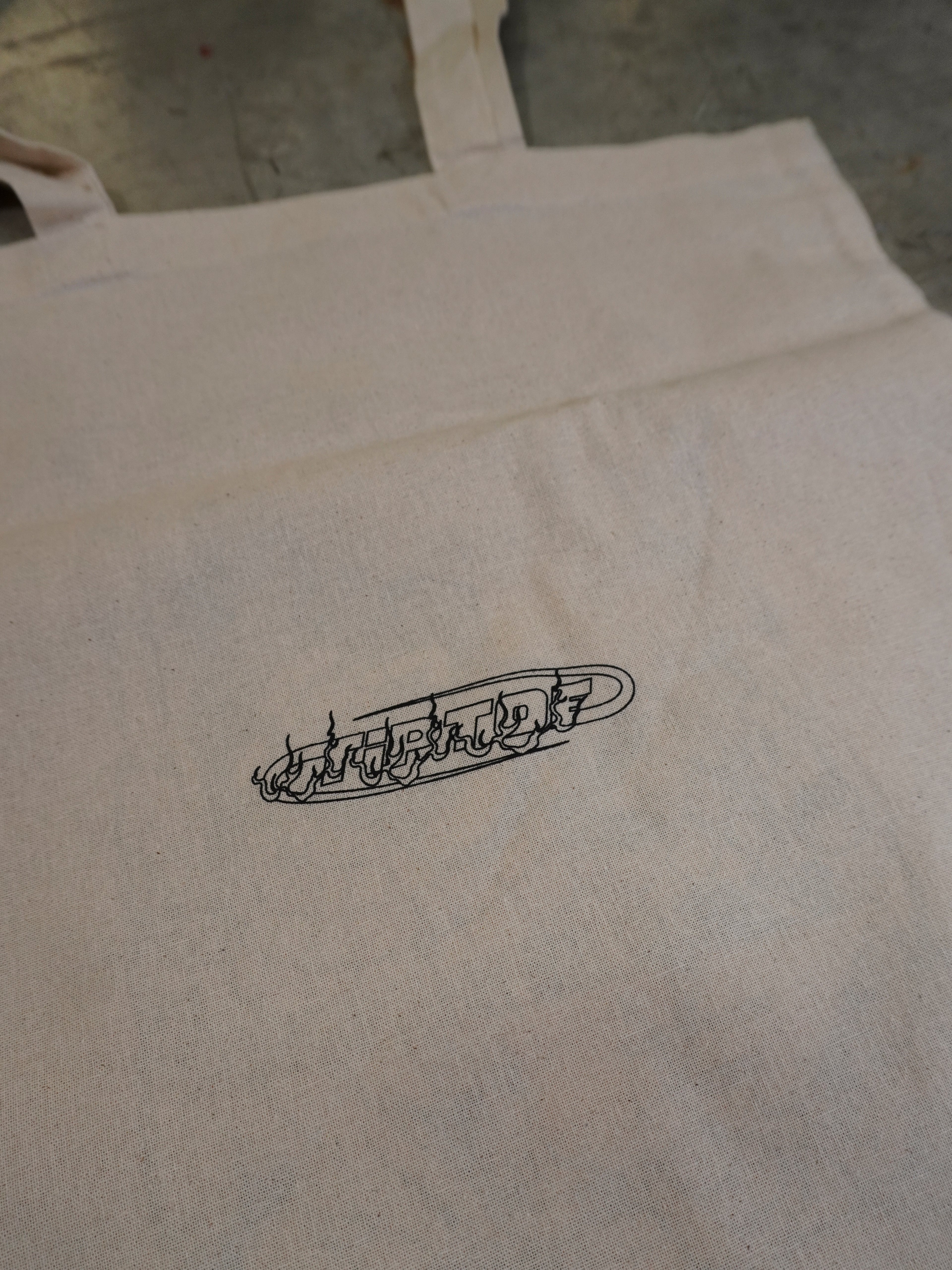 Detailaufnahme des kleinen Logos auf der naturfarbenen Baumwolltasche