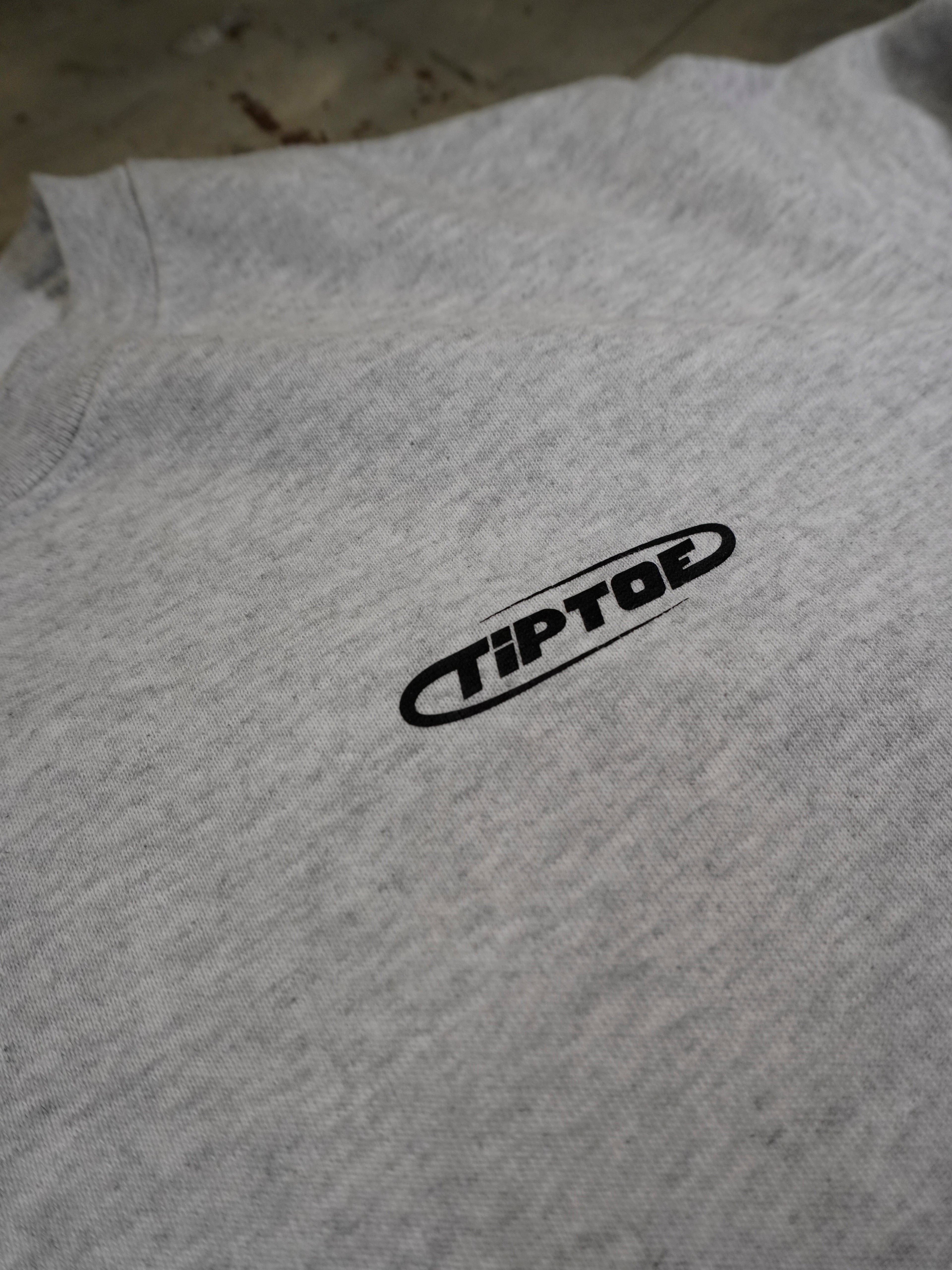 Detailaufnahme des kleinen Frontlogos auf grauem Sweater