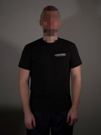 Schwarzes T-Shirt mit kleinem Frontlogo getragen von Model in klassischer Passform