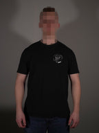 Schwarzes T-Shirt mit kleinem Brustprint getragen von Model in klassischer Passform